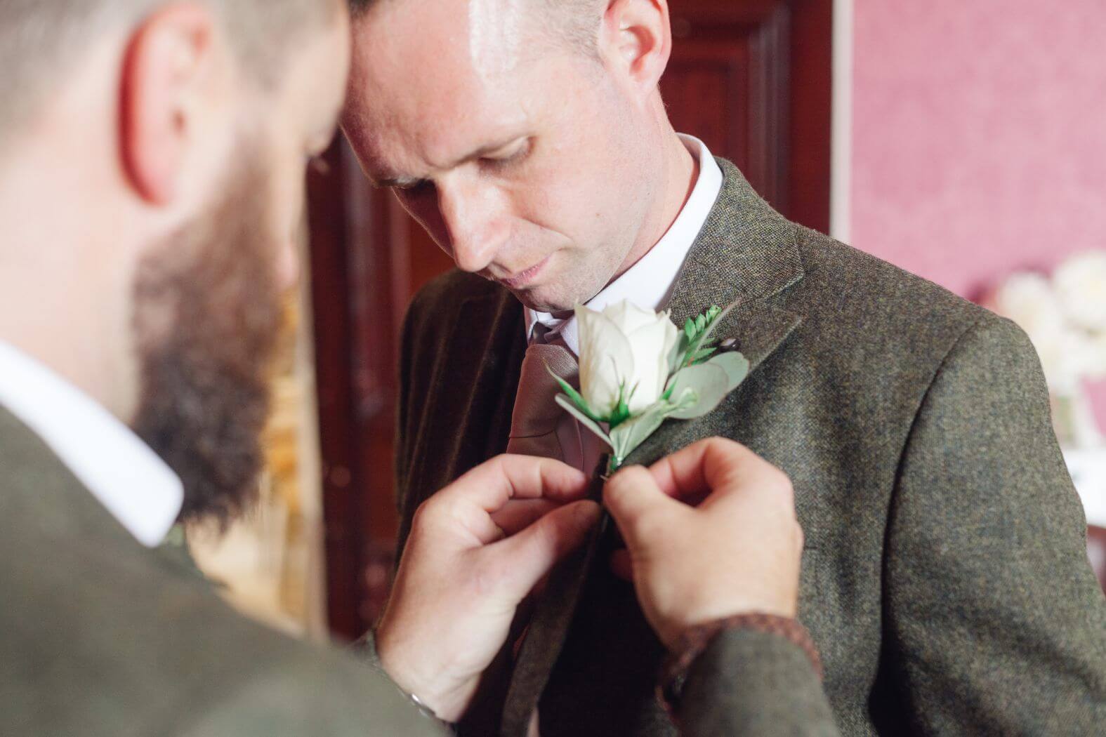 Groom pinning a buttonhole on his best man