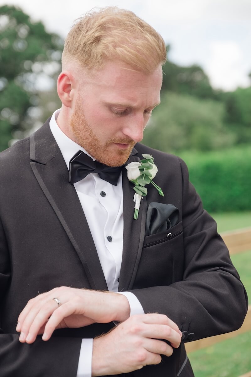 Groom adjusting his cuff in black tie