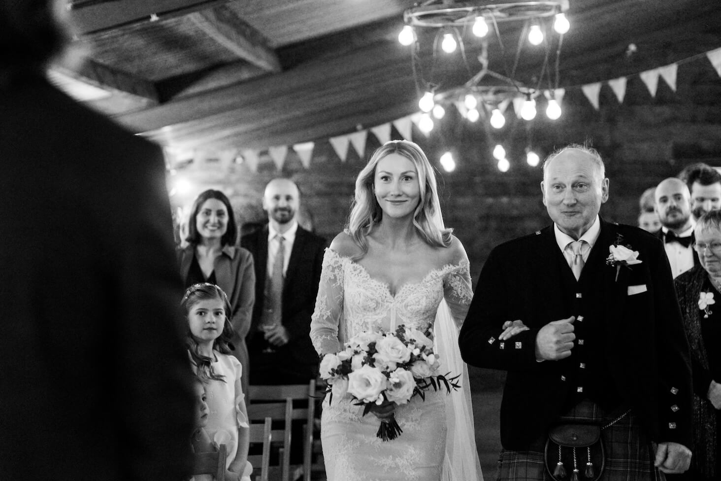 Black and white of the bride walking down the aisle with her dad at Grange Wedding Barn Cheshire