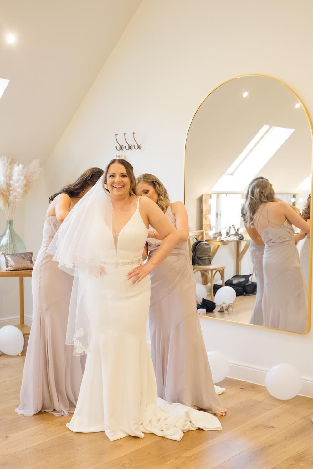 Bridesmaids helping the bride into her dress at Hyde House