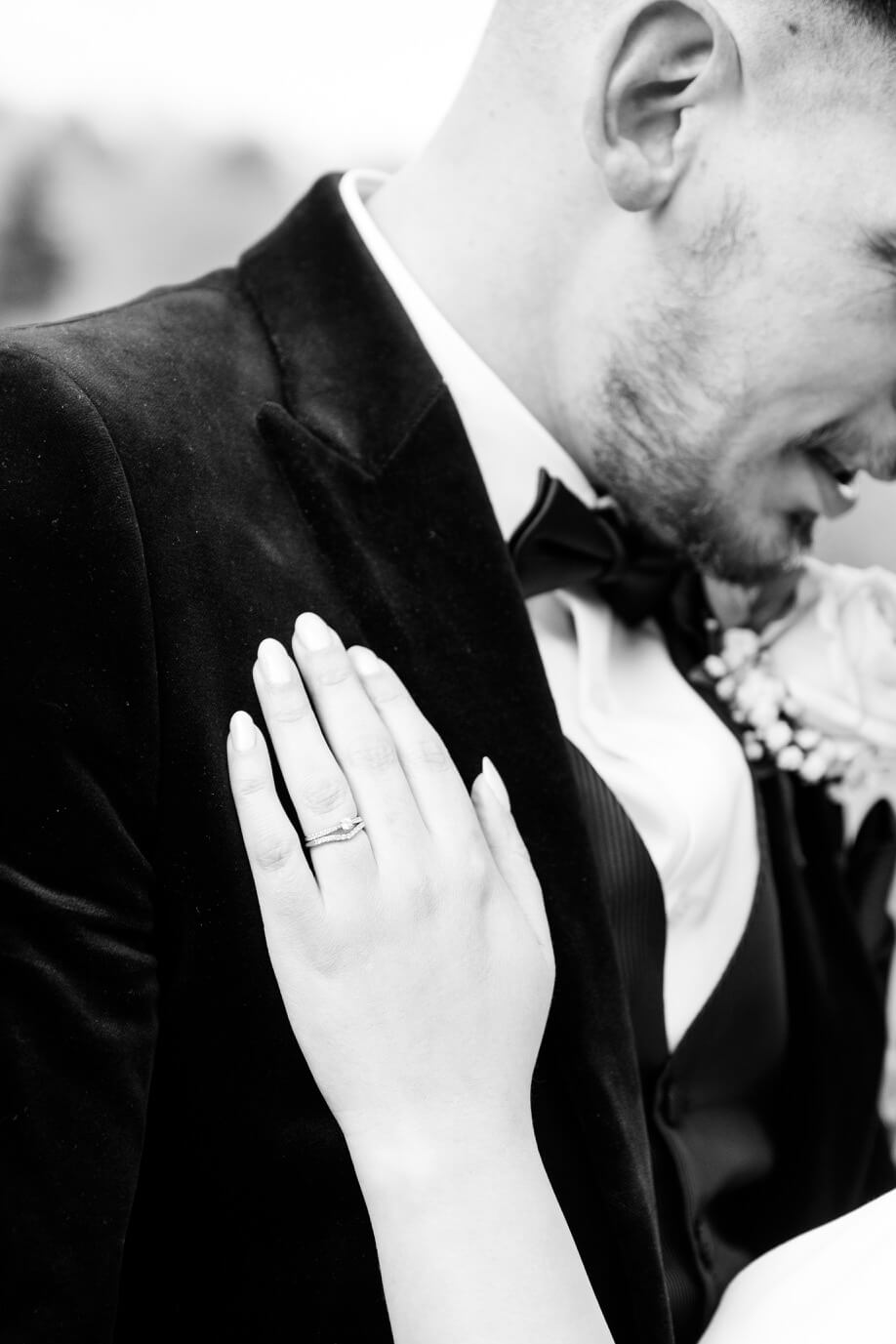 Black and white portrait of the groom with the bride's hand on his shoulder at Hyde House