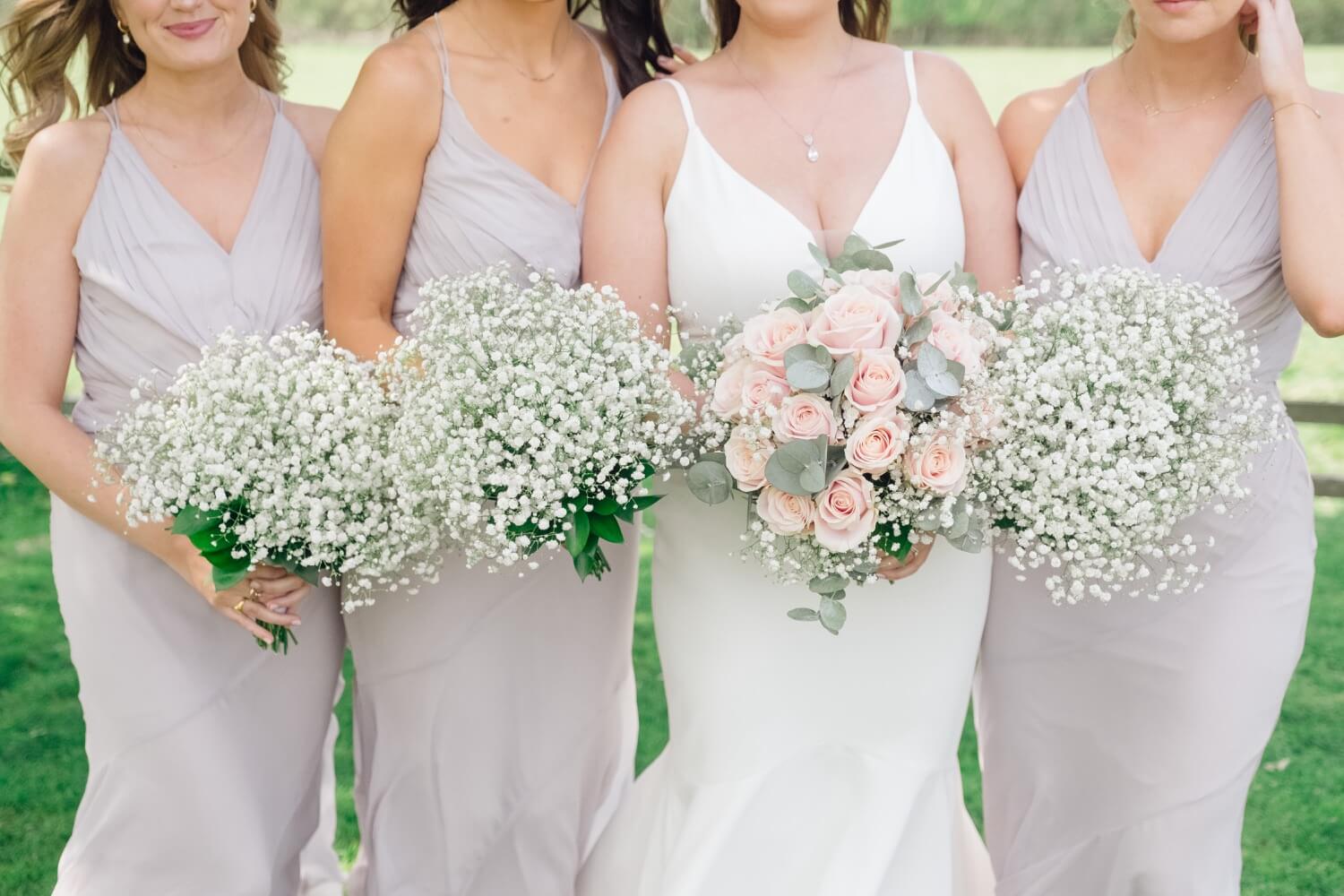 Bride and bridesmaids showing their bouquets at Hyde House