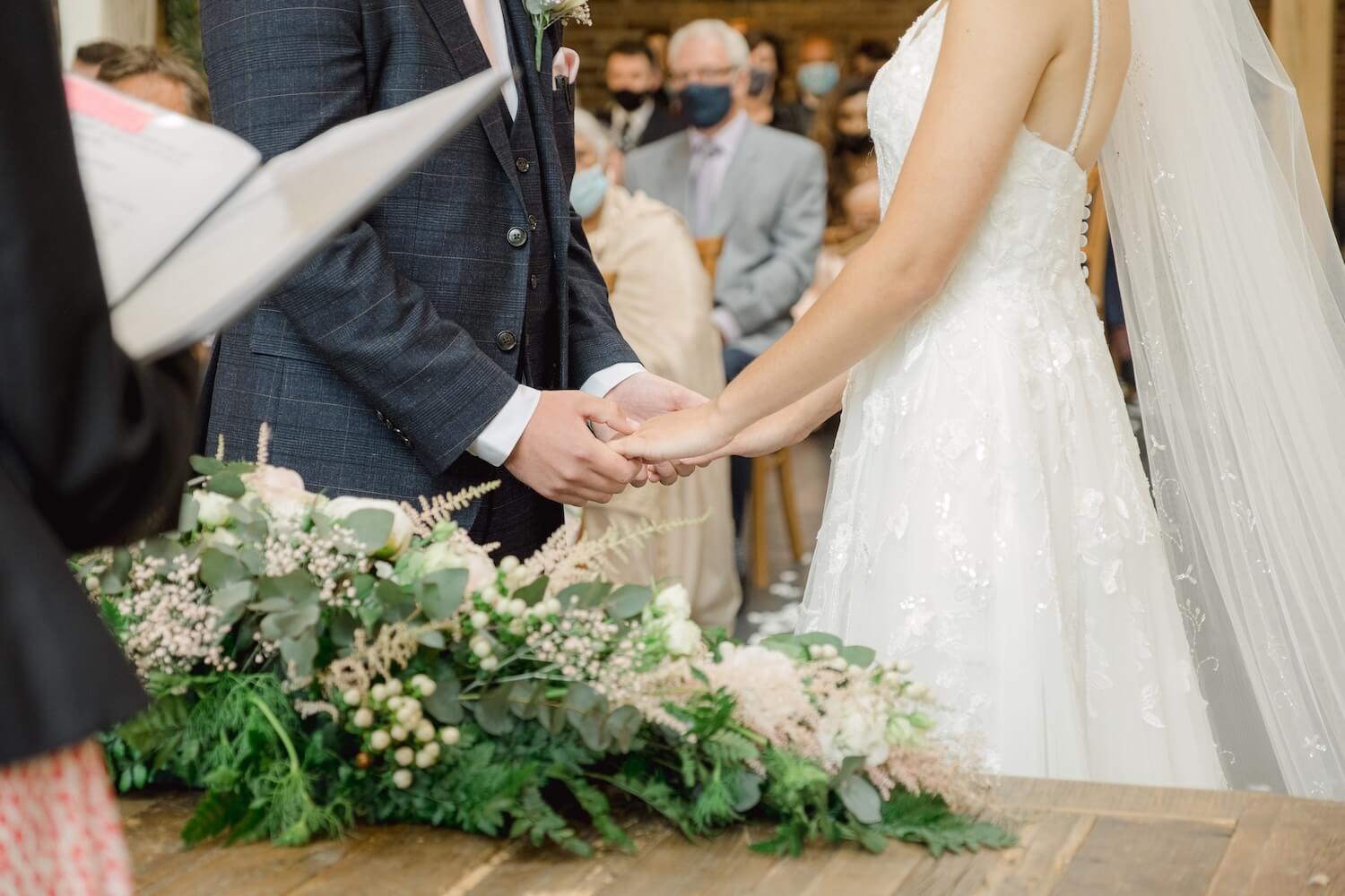 Bride and groom holding hands during their Mythe Barn ceremony