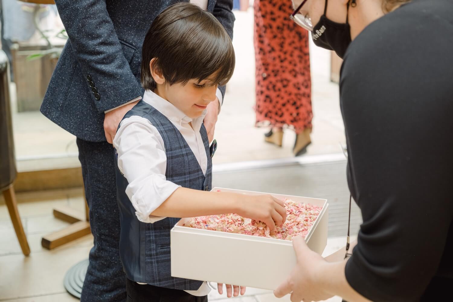 Page boy gathering confetti at a Mythe Barn wedding