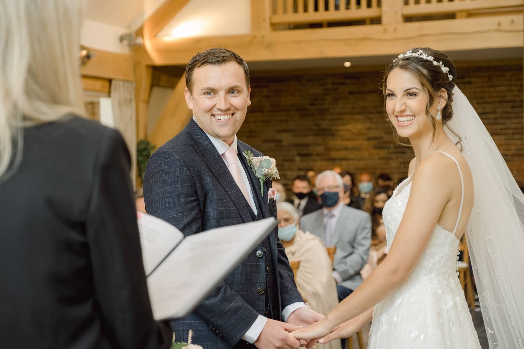 Wedding ceremony in the oak barn at Mythe Barn, bride and groom holding hands