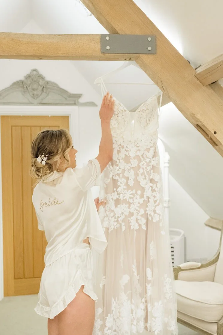 Bride with her hanging wedding dress at Stratton Court Barn