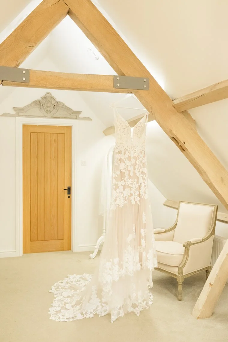 Bride's dress hanging in the barn venue at Stratton Court Barn wedding photography