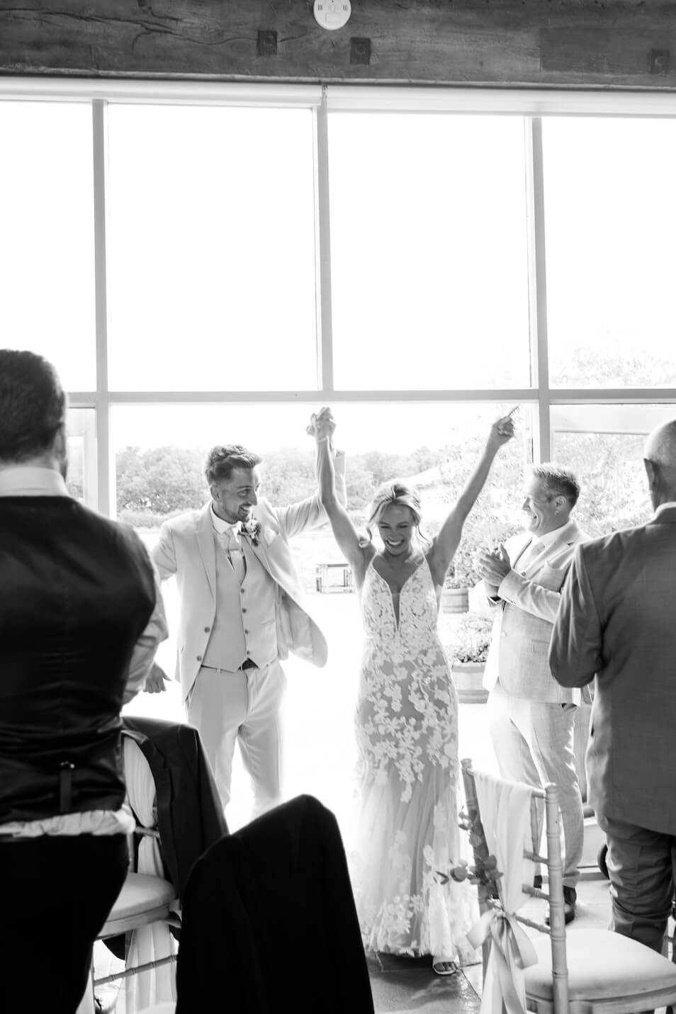 Black and white of the bride and groom entering the wedding breakfast at Stratton Court Barn