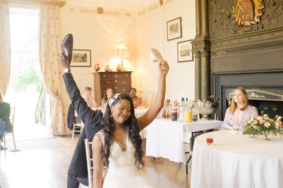 Couple sitting back to back holding shoes during the Mr and Mrs shoe game