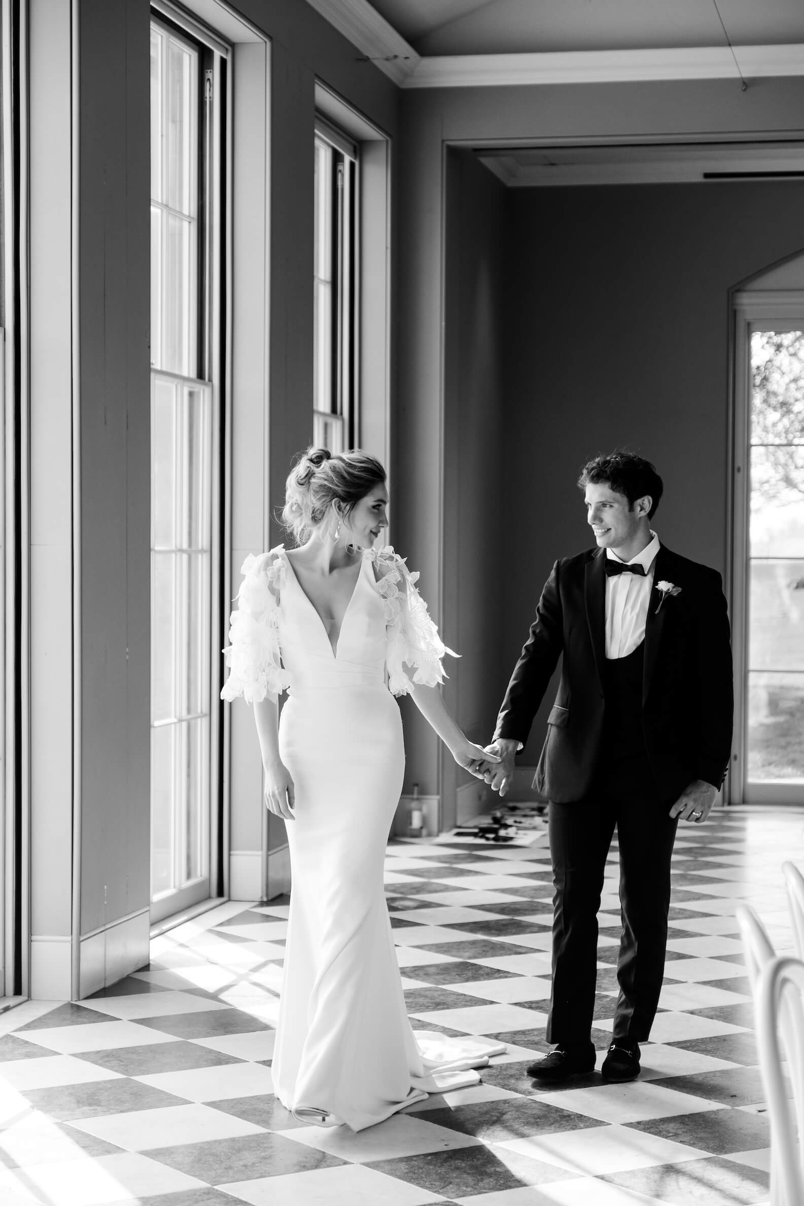 Black and white wedding photo of a bride and groom, the bride's dress and floral sleeve detail in frame