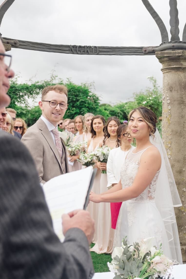 Bride and groom holding hands during their Birtsmorton Court wedding ceremony