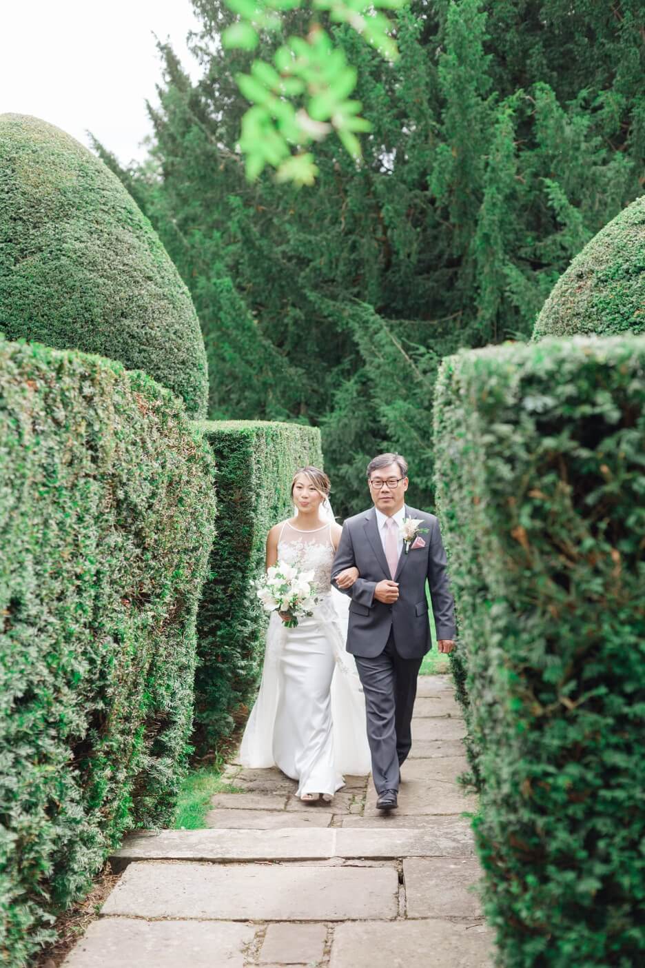 Bride and her father walking towards the White Garden ceremony at Birtsmorton Court