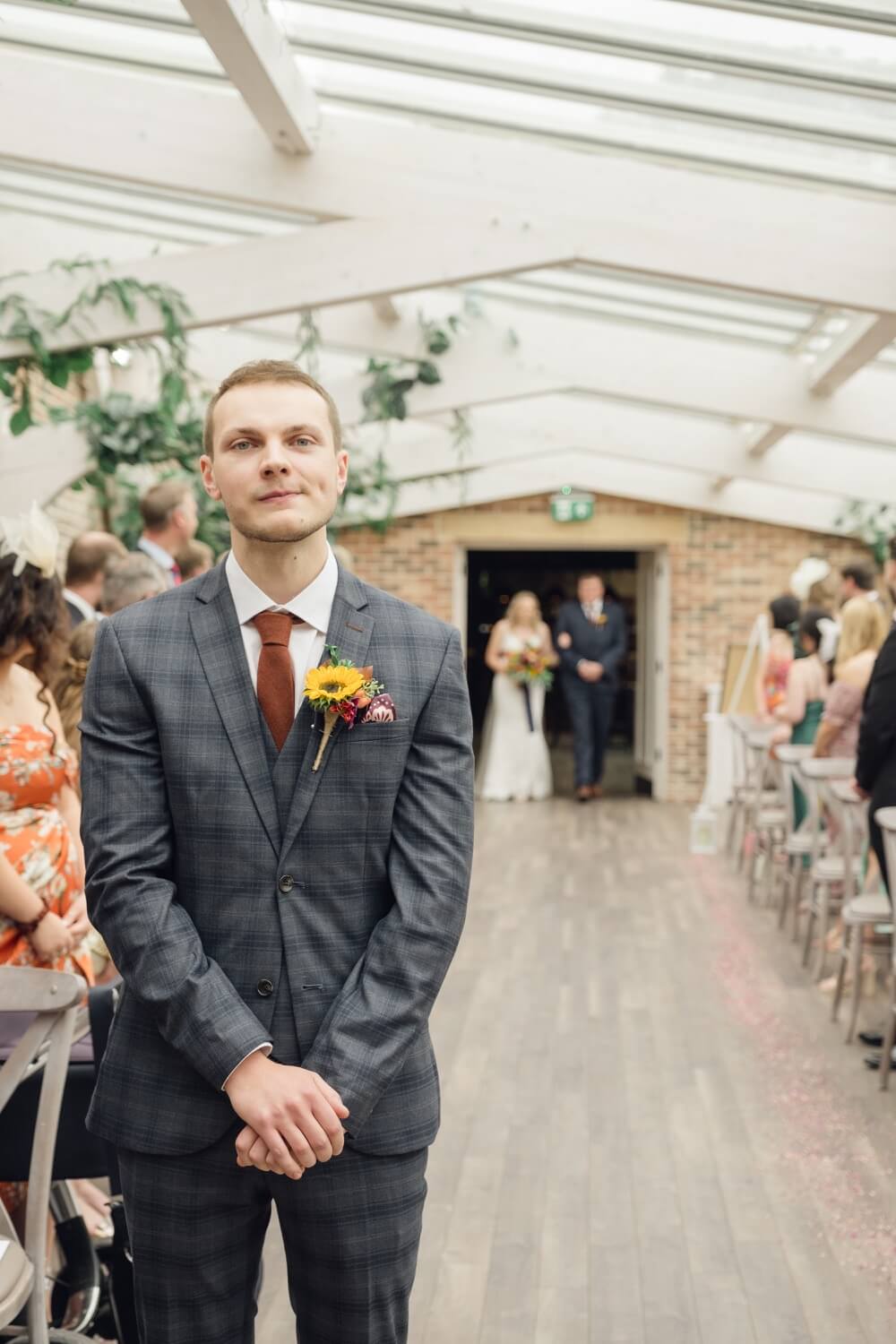 Groom waiting at the front as the bride arrives with her father at Foxtail Barns