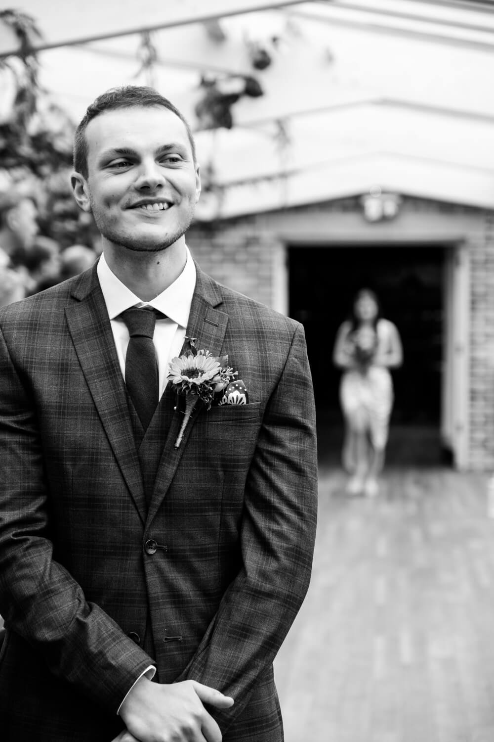 Groom watching a bridesmaid make her way down the aisle