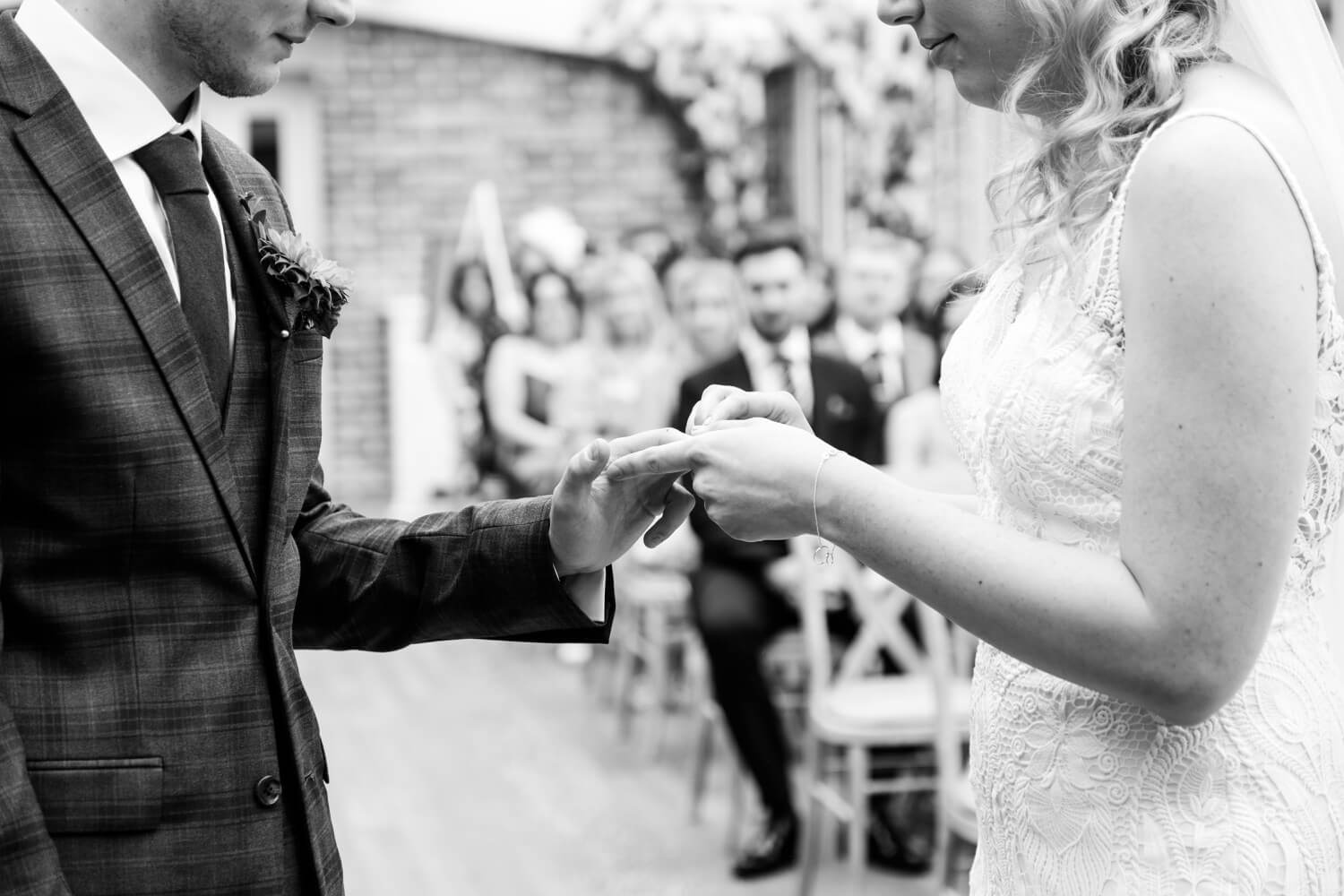 Placing the wedding ring on the bride's finger at Foxtail Barns