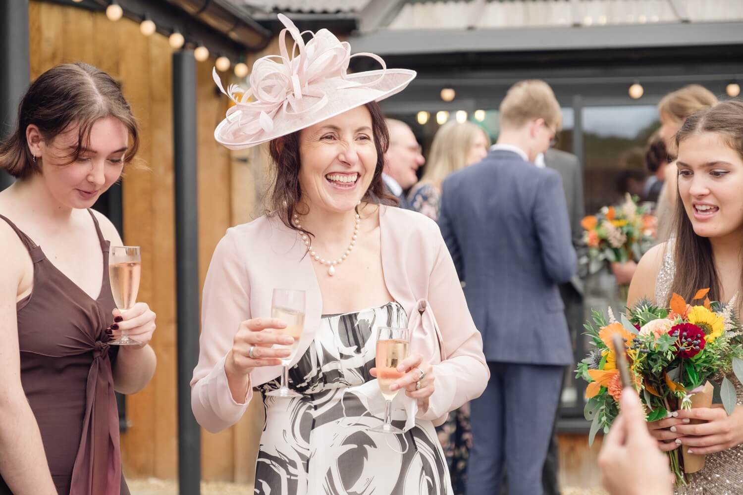 Guests in wedding hats laughing in the walled garden at Foxtail Barns