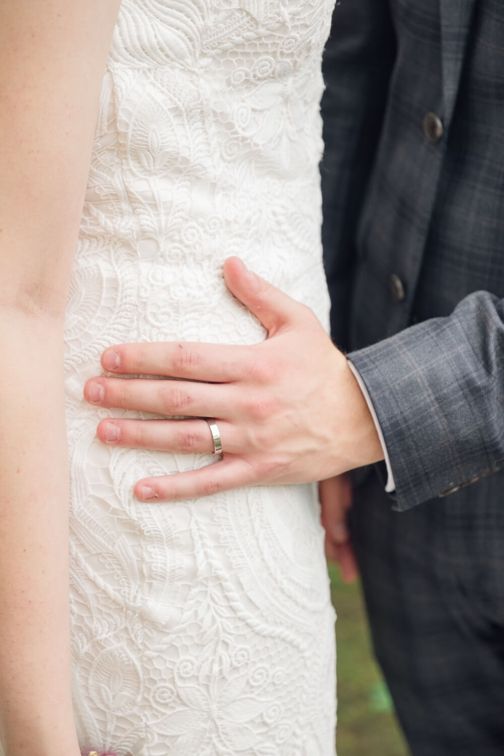 Close-up of the groom's hand at the bride's waist during portraits