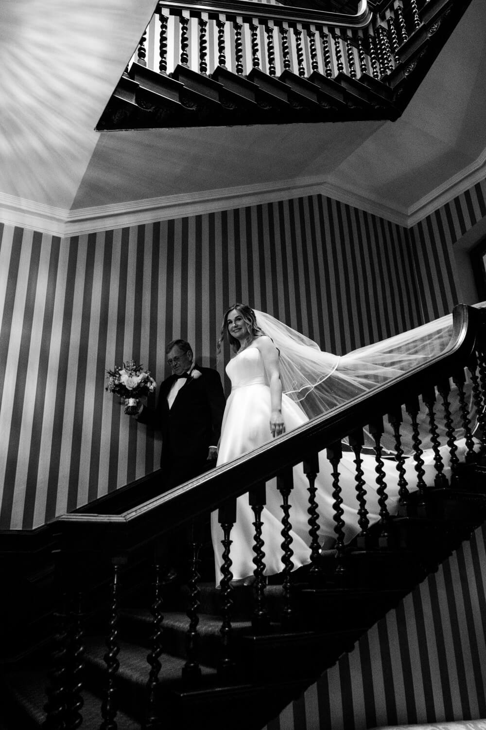 Bride coming down the stairs with her father at Hawkstone Hall