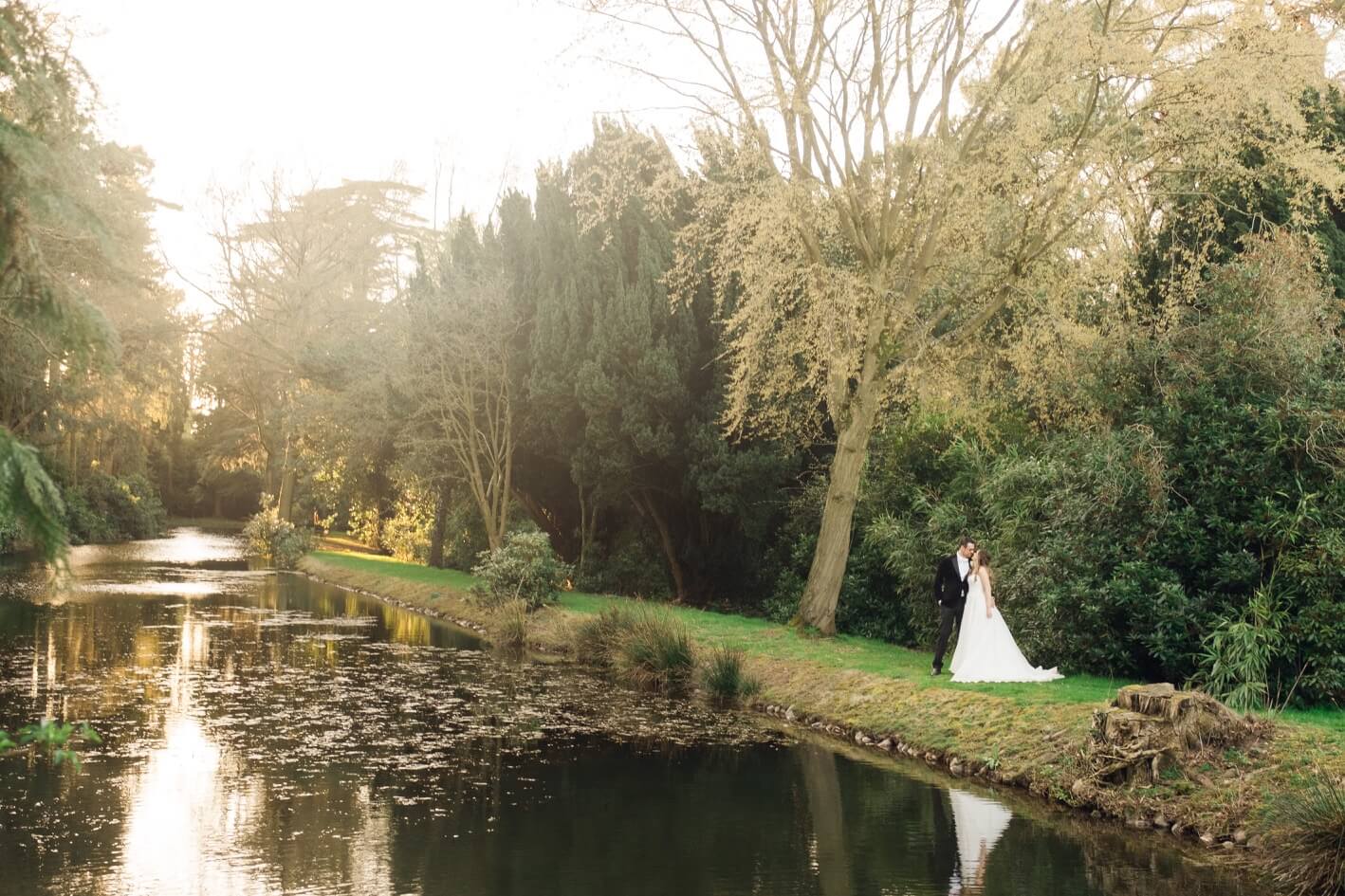 Bride and groom by the river in the grounds at Hawkstone Hall