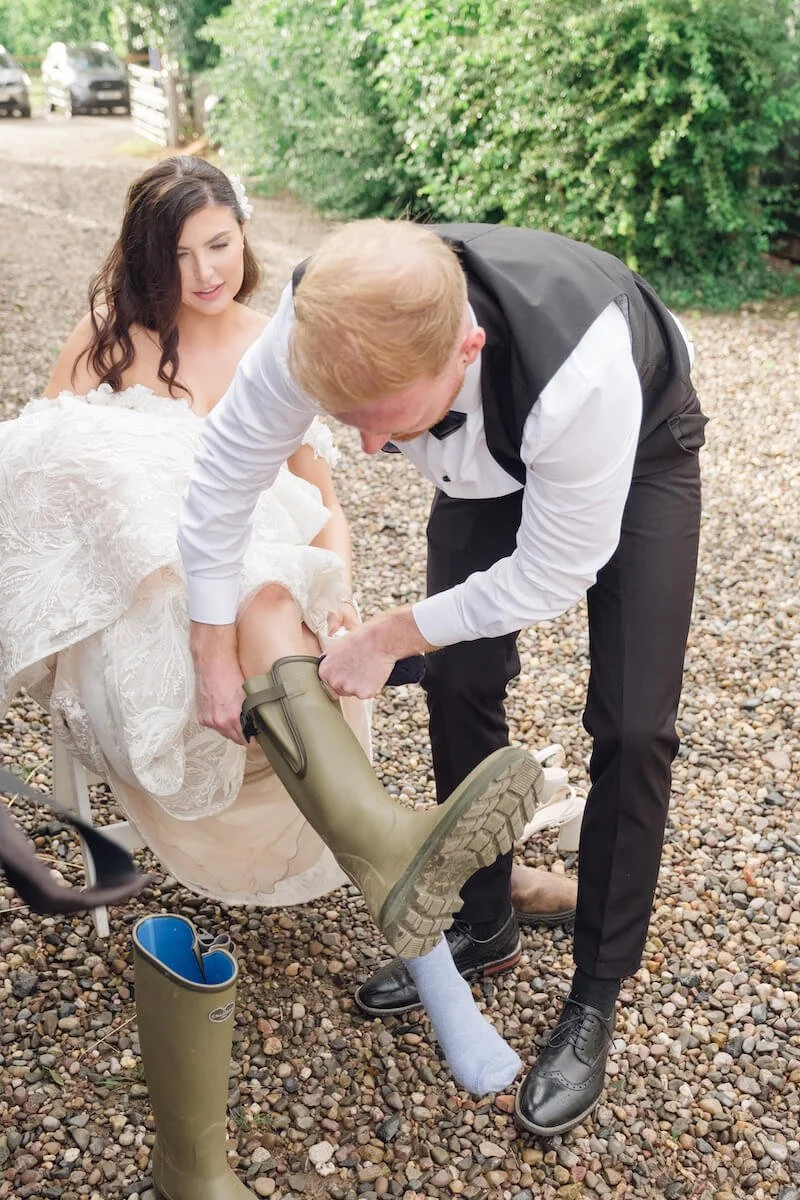 Groom helping the bride into her wellies