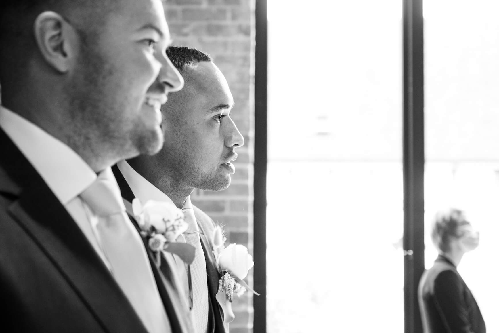 Groom and best man waiting in the redbrick barn at a Redhouse Barn wedding ceremony