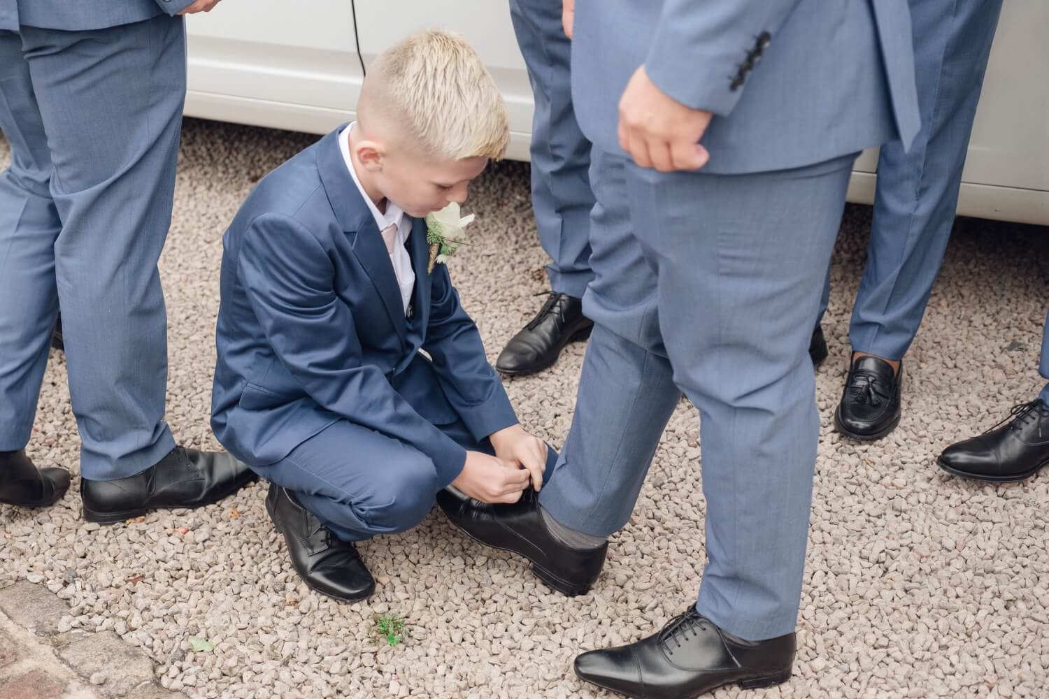 Young boy tying shoe laces for his granddad before the ceremony