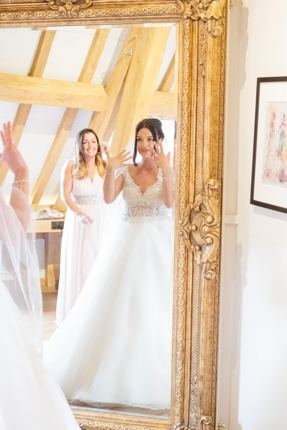 Bride in her wedding dress looking in the mirror at Redhouse Barn