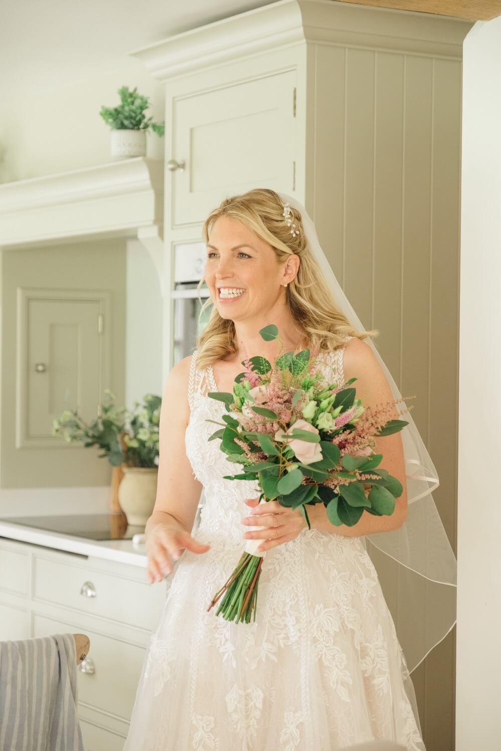 Smiling bride holding her bouquet during bridal preps before her Shustoke Barn wedding