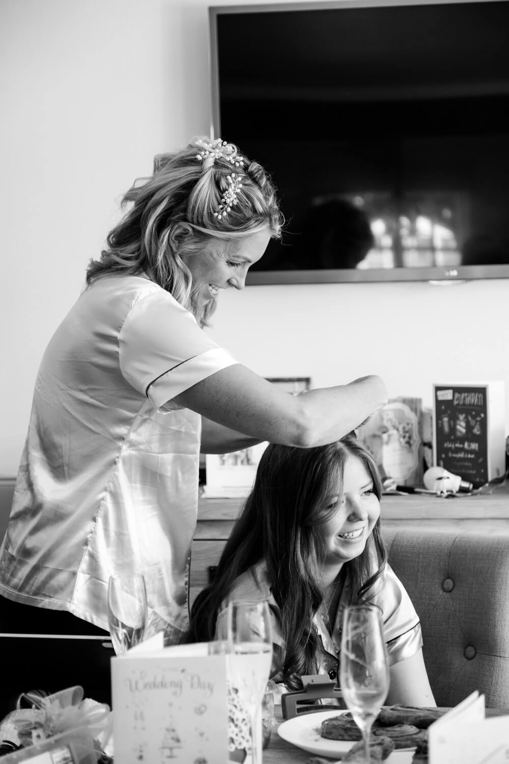 Bride helping style her bridesmaid's hair on the wedding morning