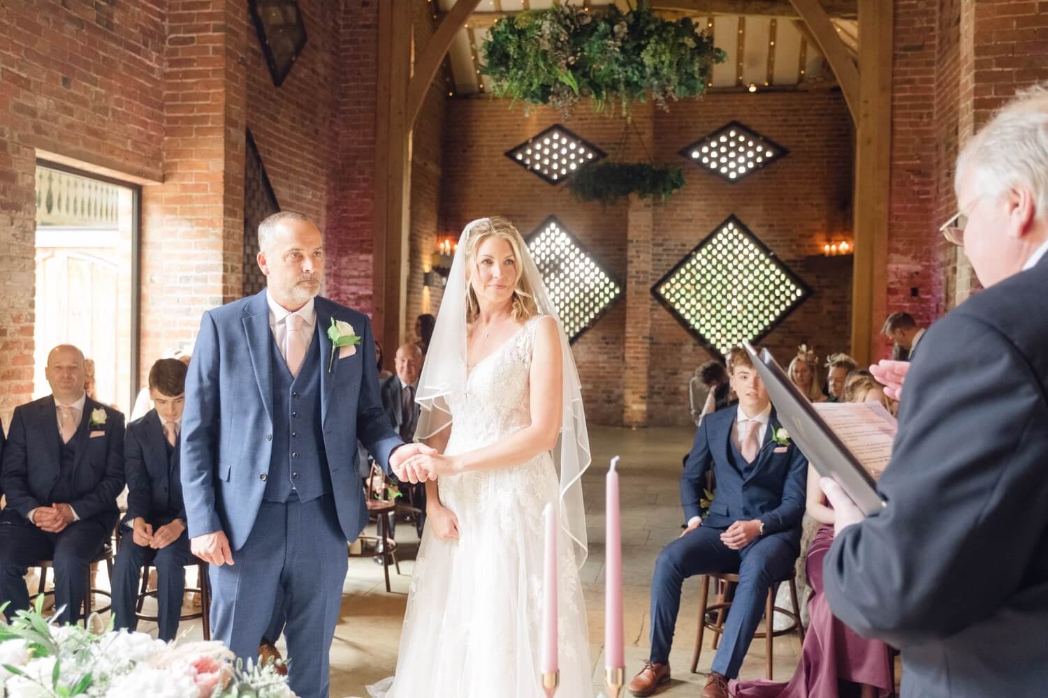 Close-up of the couple holding hands as they exchange vows at Shustoke Barn