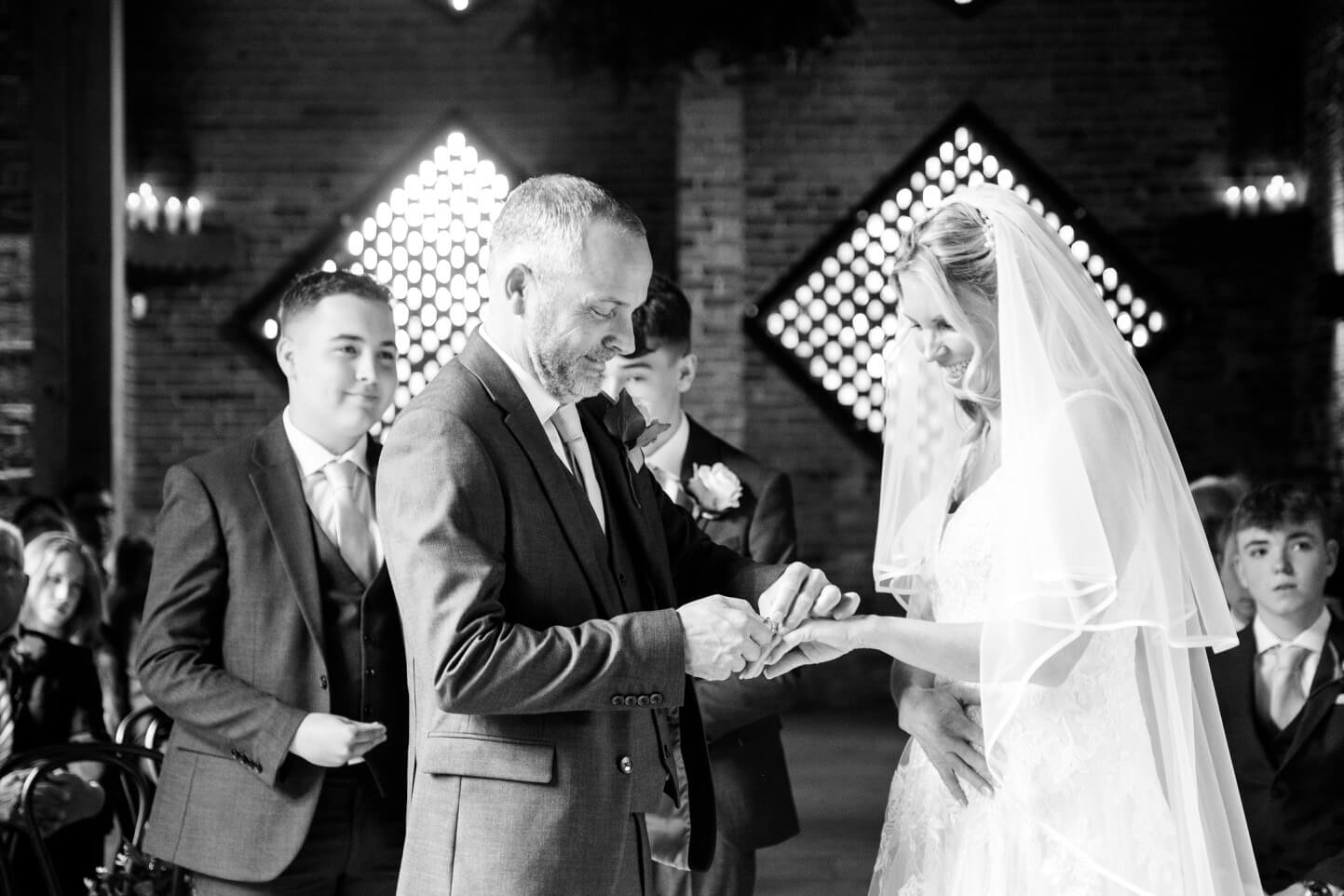 Placing the wedding ring on the bride's finger at Shustoke Barn