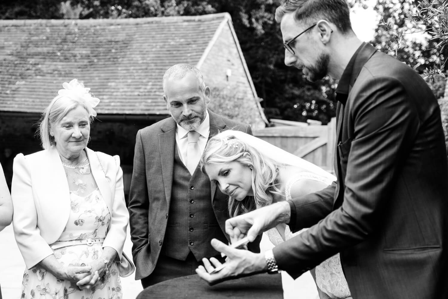 Bride watching the wedding magician perform at Shustoke Barn