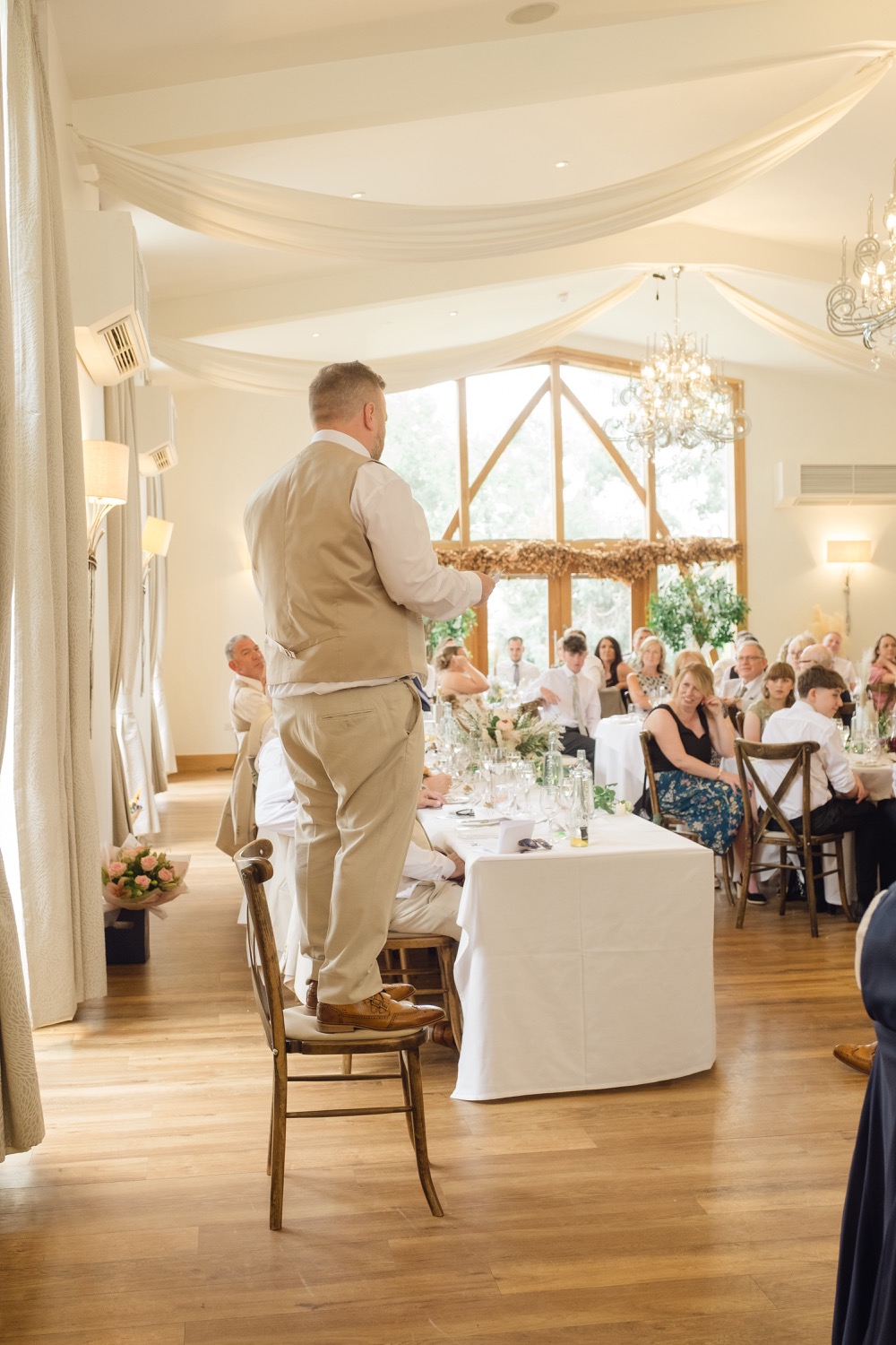 The best man giving a speech from a chair at Mythe Barn