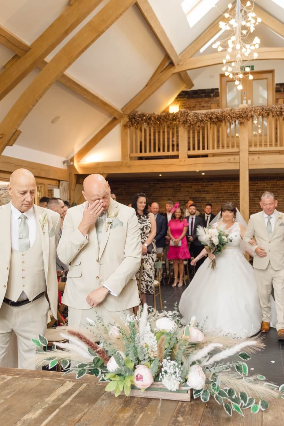 The groom wiping away a tear as the bride arrives