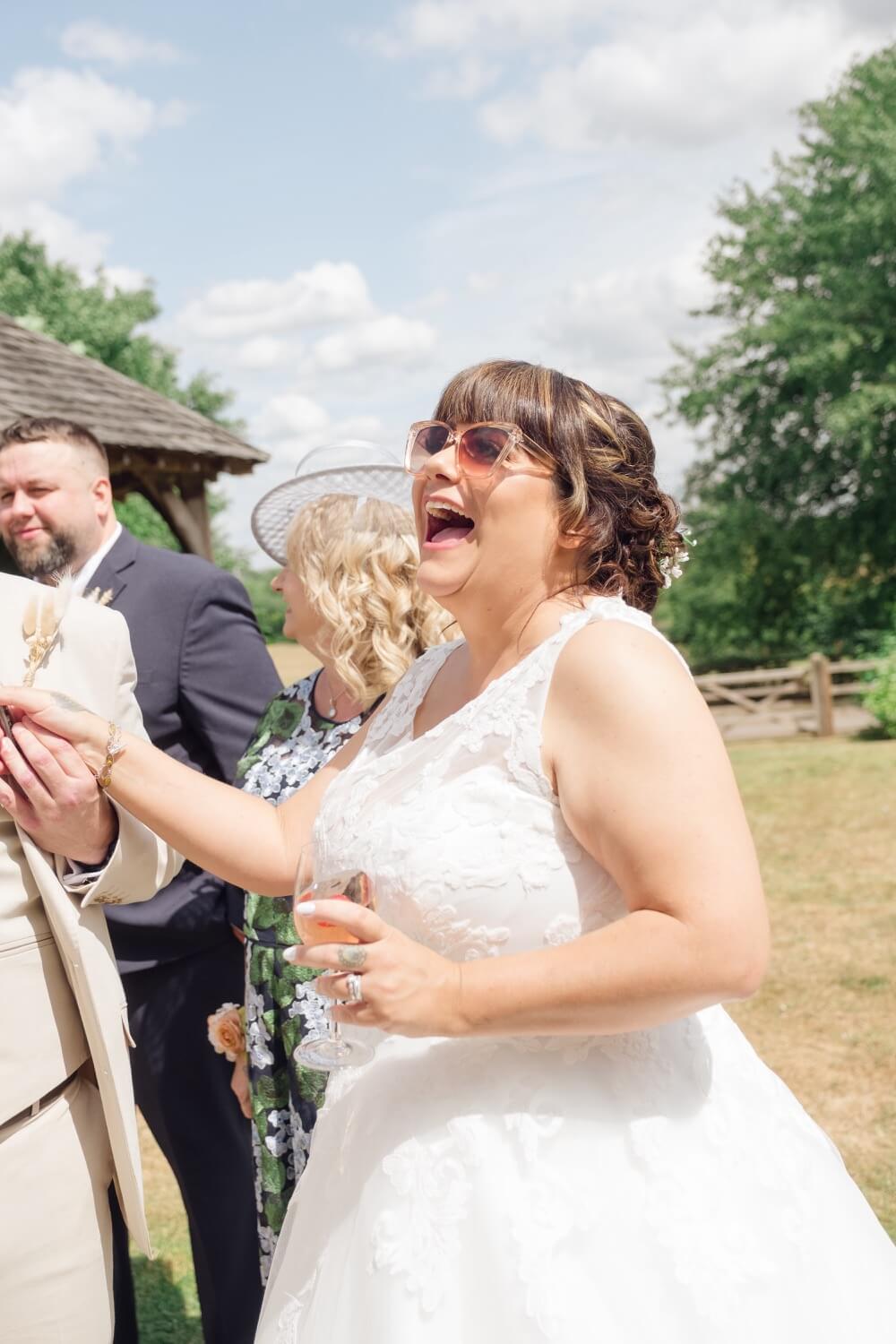The bride laughing during the drinks reception at Mythe Barn