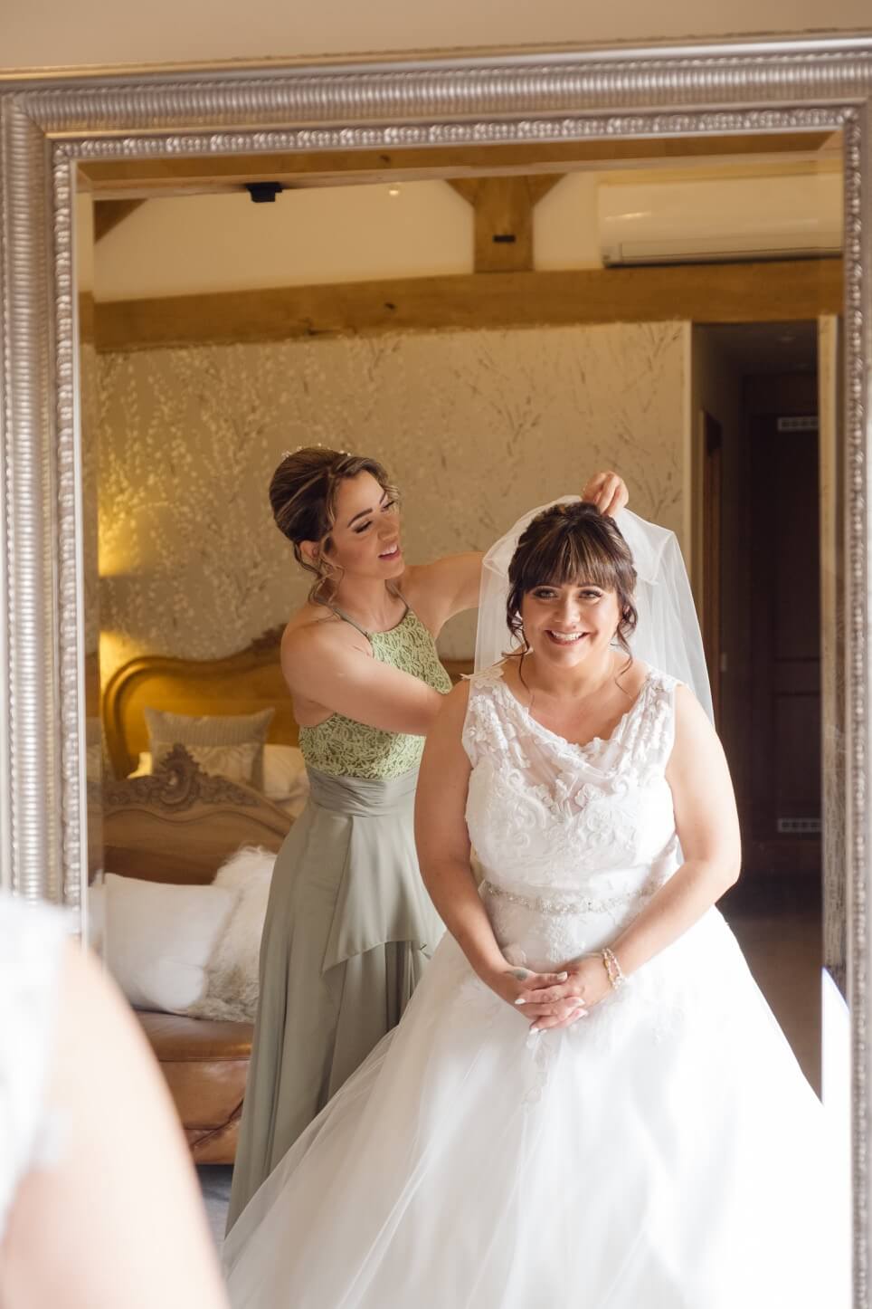 The bride in her dress with a bridesmaid helping