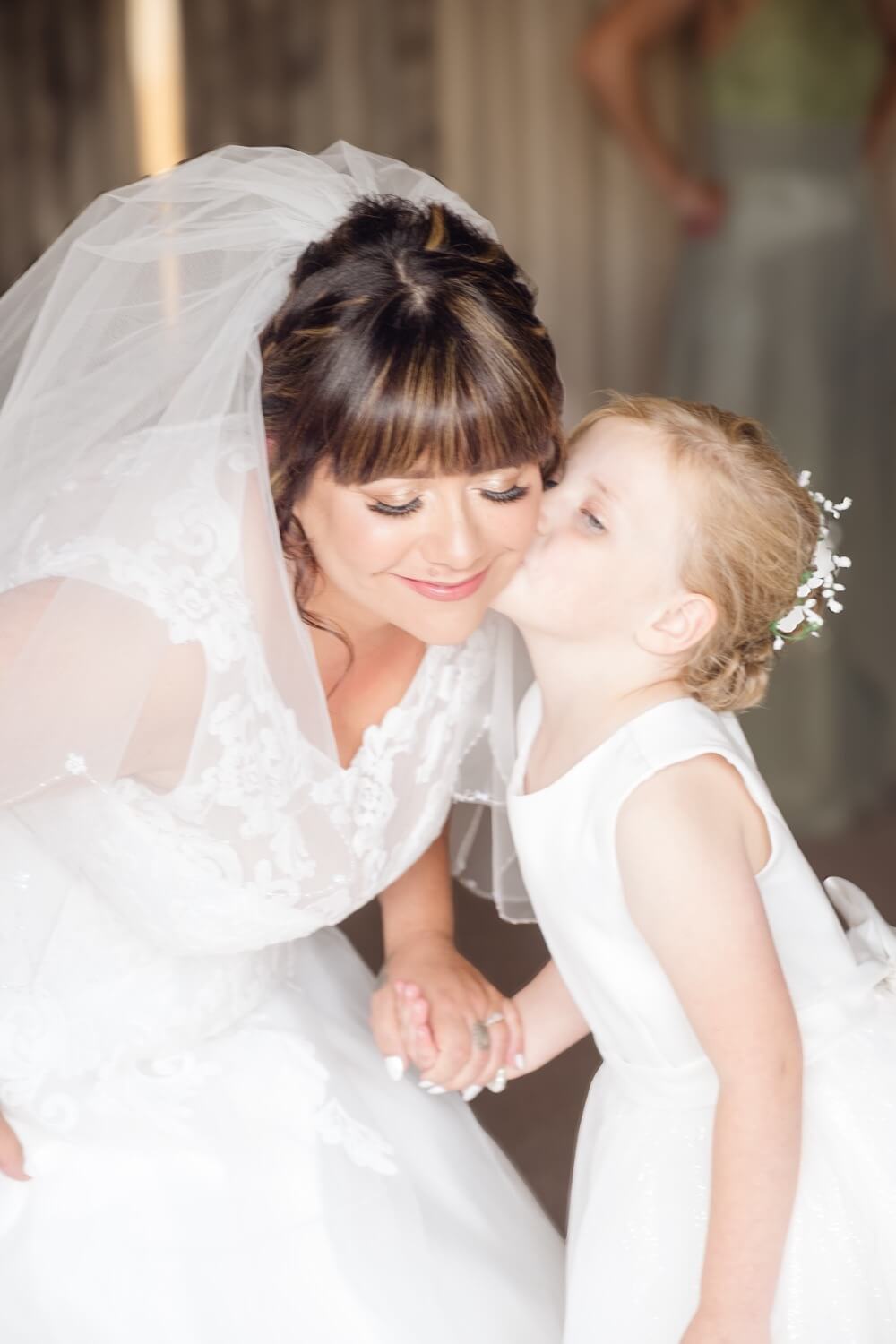 The flower girl giving the bride a kiss