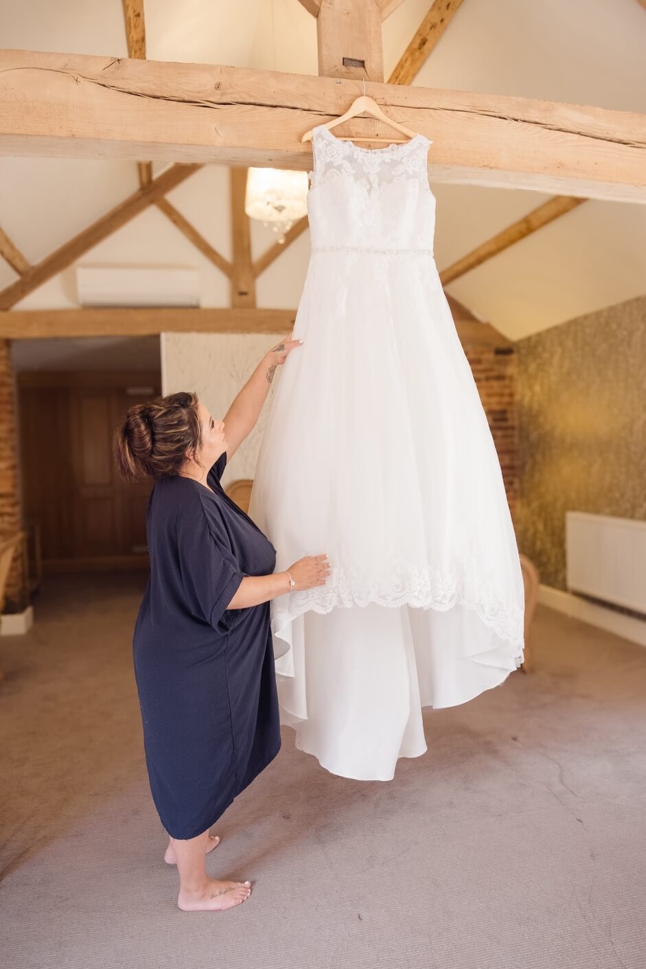 The bride beside her hanging wedding dress