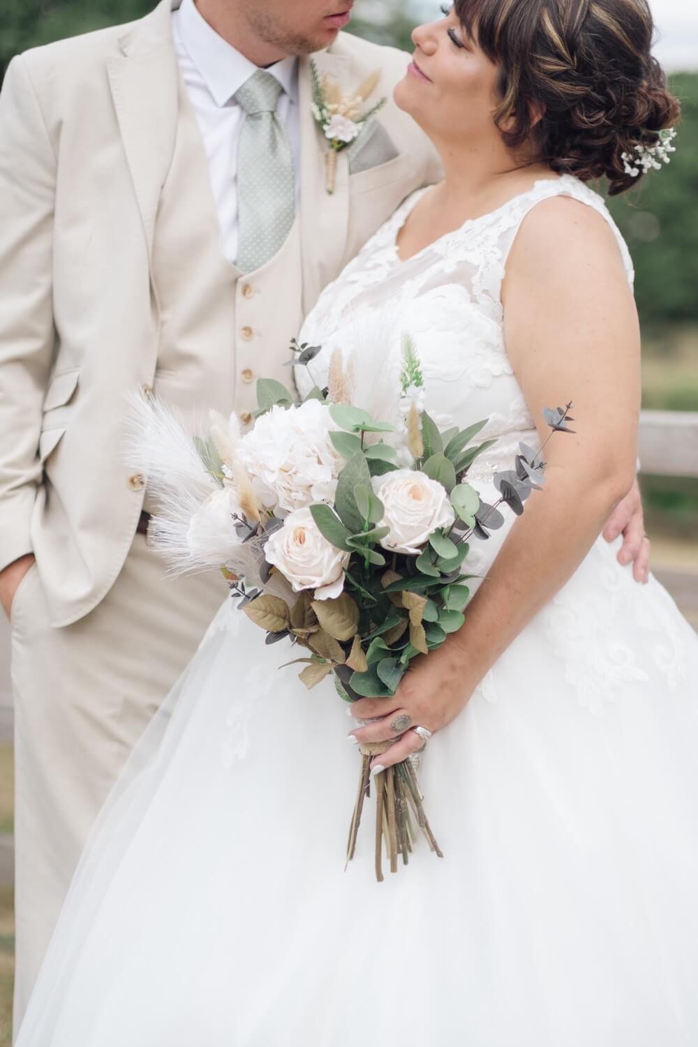 The bride and groom with the bouquet in focus at Mythe Barn