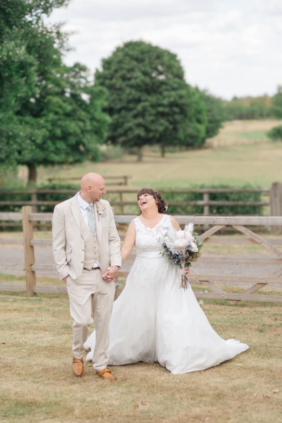 Hayley and Dan walking hand in hand and laughing in the grounds