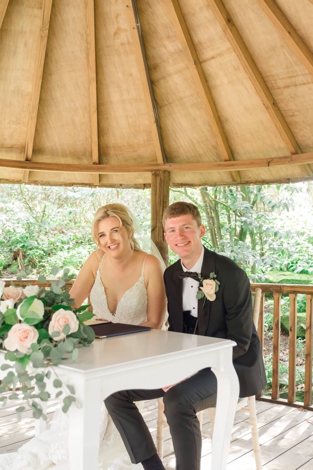 Bride and groom smiling as they sign the register