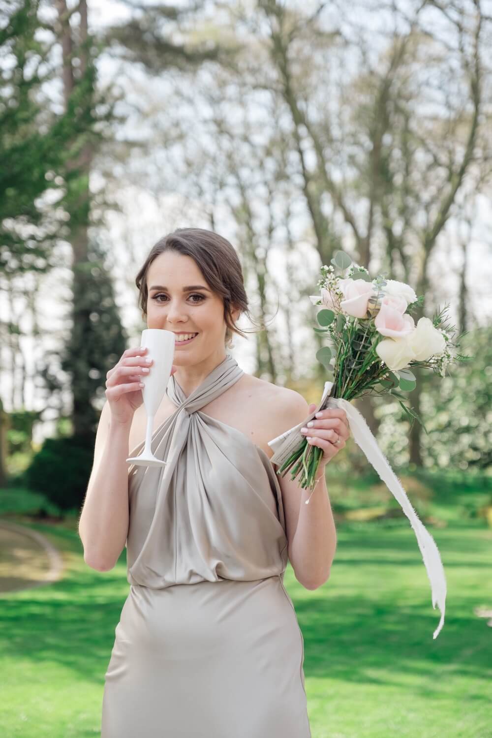 Bridesmaid with a glass of champagne in the gardens