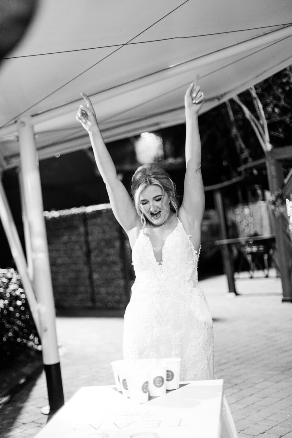 Bride celebrating during a game of beer pong at Moxhull Hall