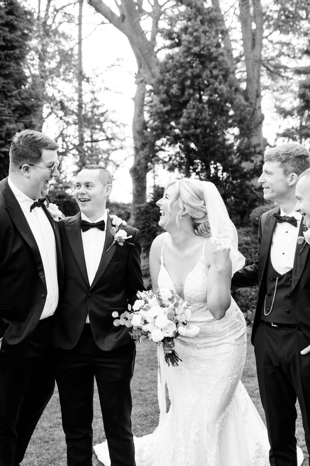 Bride laughing with the groom's party at Moxhull Hall