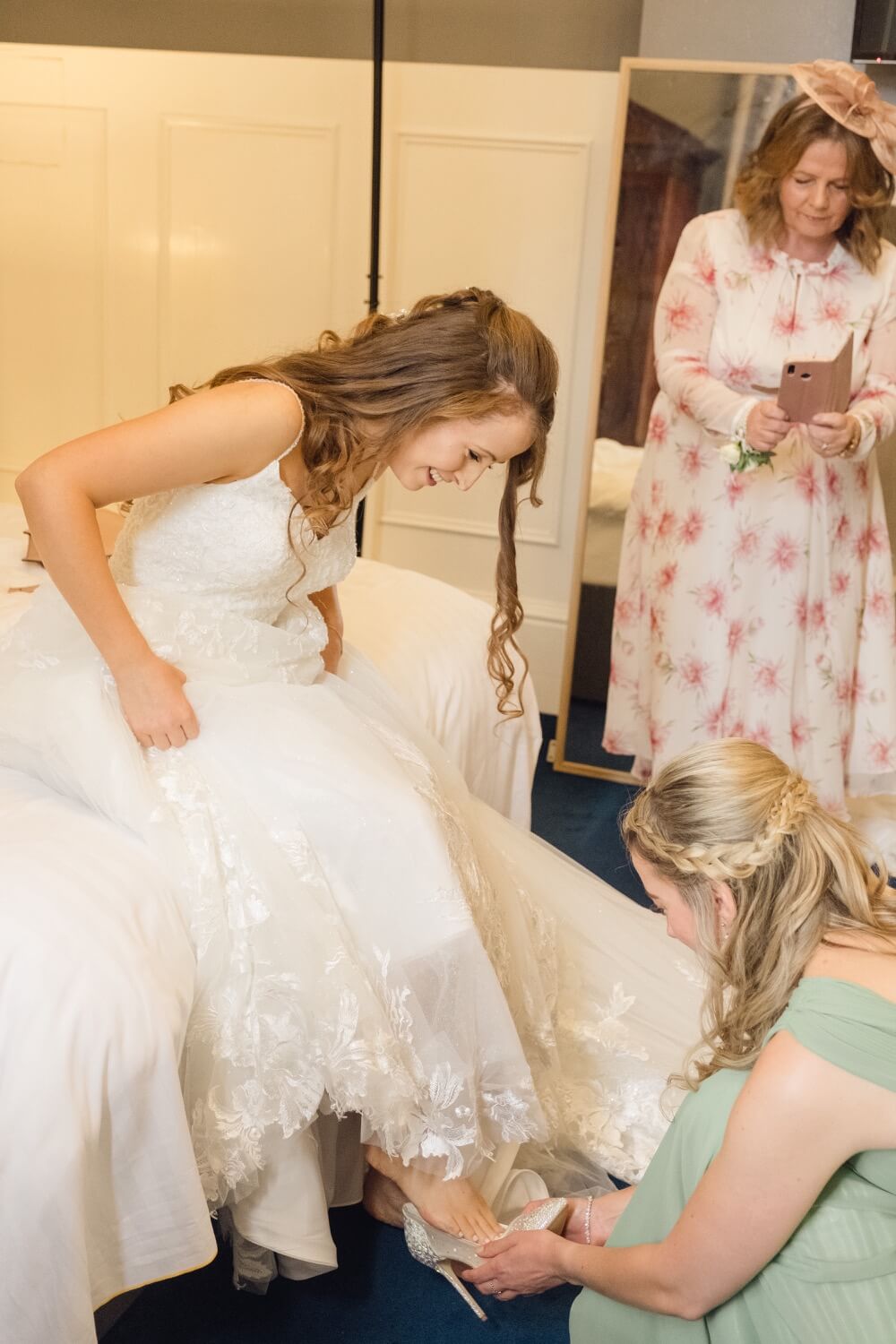 A bridesmaid helping with the bride's shoe
