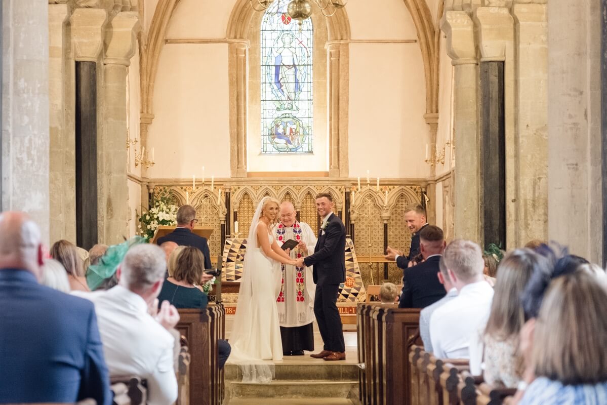 Bride and groom holding hands during the ceremony near The Great Barn, Aynho