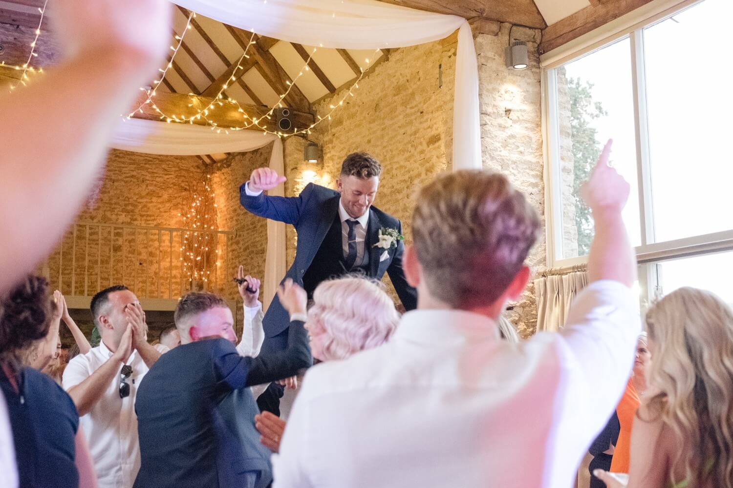 Groom crowd surfing during the evening reception at The Great Barn, Aynho