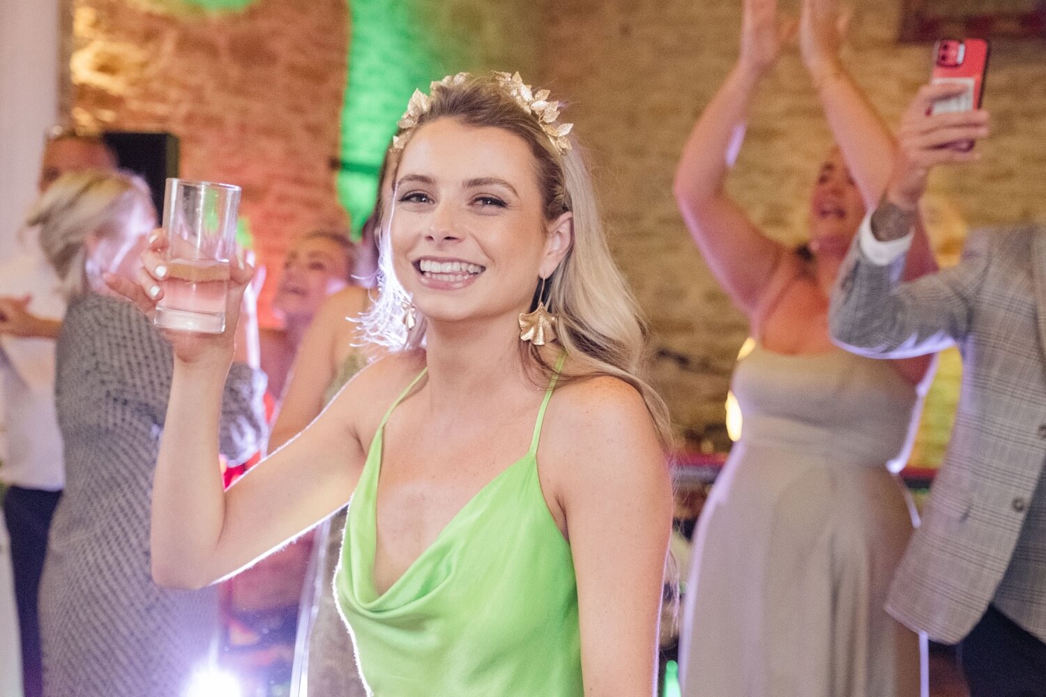 Guest smiling with a drink during the evening reception at The Great Barn, Aynho