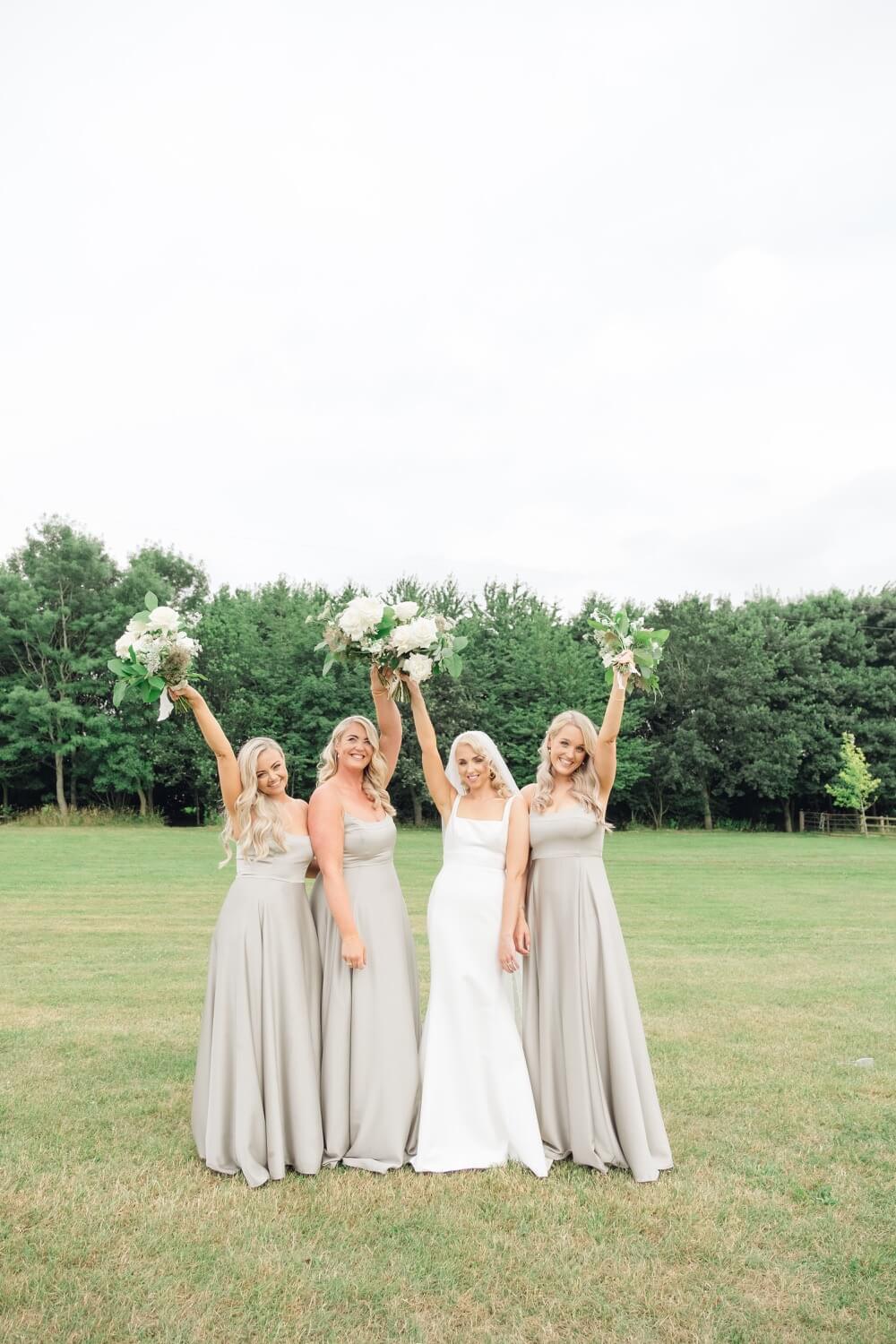 Bride with her bridesmaids holding flowers at The Great Barn, Aynho
