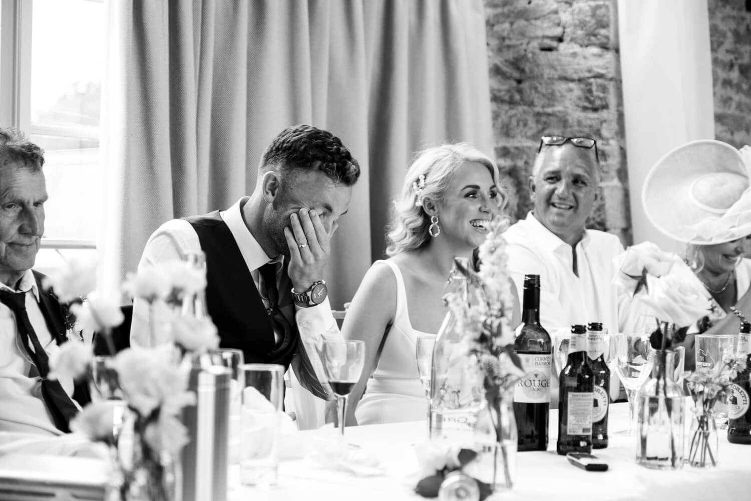 Groom reacting during the best man's speech at The Great Barn, Aynho